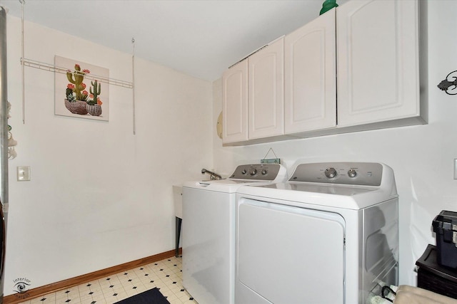 clothes washing area with cabinets and washer and clothes dryer