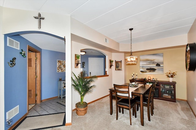 carpeted dining room with an inviting chandelier