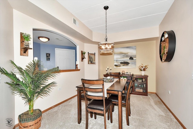 dining space featuring a notable chandelier and light colored carpet