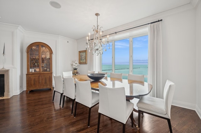 dining space featuring an inviting chandelier, dark wood-type flooring, ornamental molding, and a water view