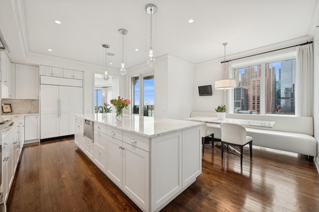 kitchen with light stone counters, decorative light fixtures, a center island, and white cabinets