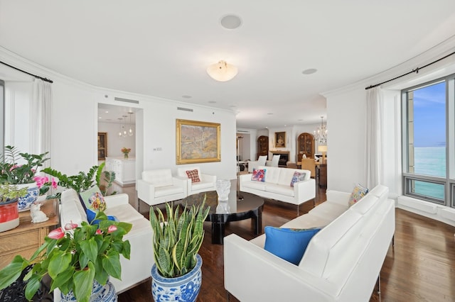 living room with a water view, crown molding, dark wood-type flooring, and a notable chandelier