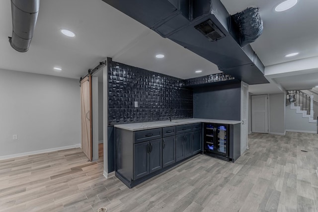 bar featuring a barn door, sink, and light hardwood / wood-style flooring