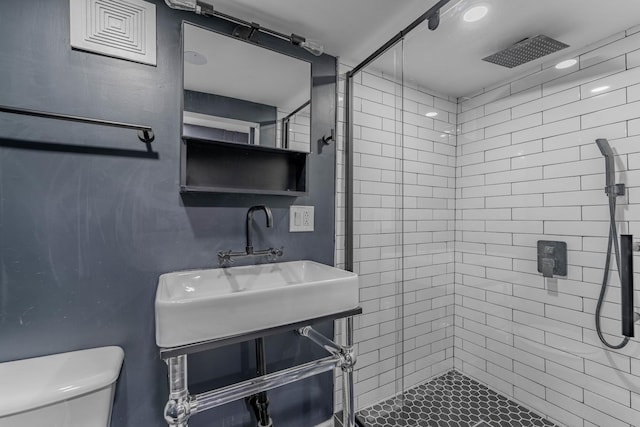 bathroom with sink, toilet, and tiled shower