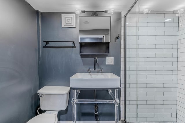 bathroom featuring sink, toilet, and tiled shower