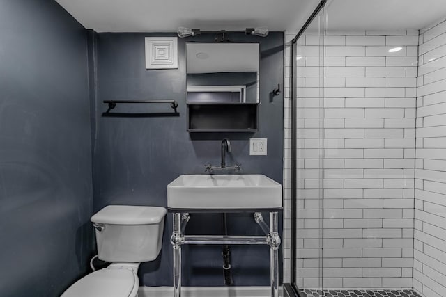 bathroom featuring toilet, sink, and a tile shower