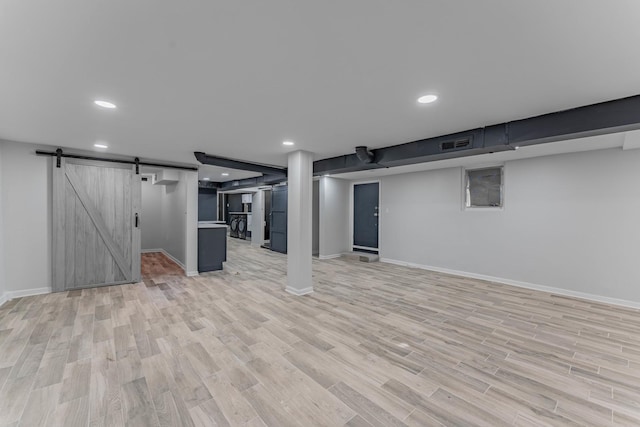 basement with light hardwood / wood-style floors and a barn door