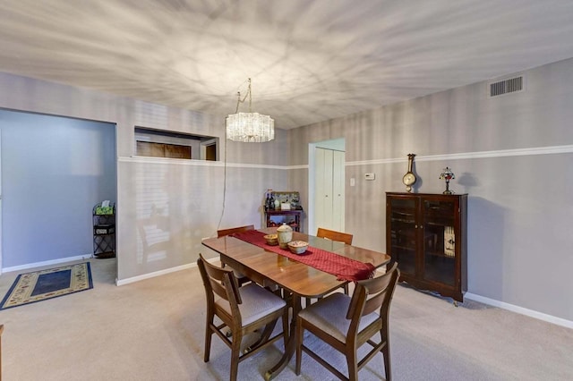 dining area with light carpet and a notable chandelier