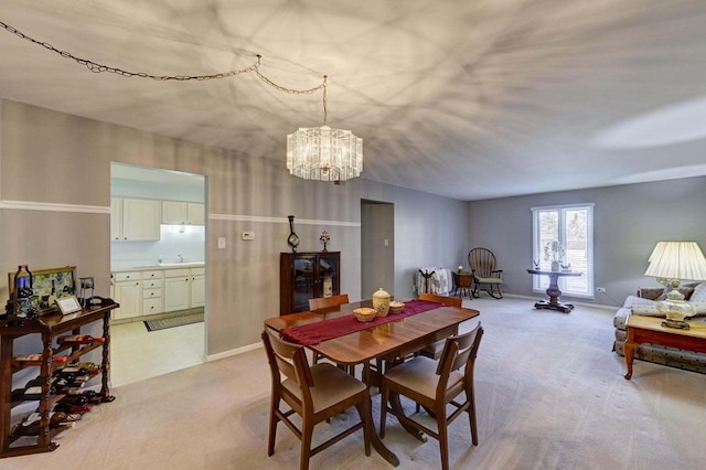 dining space with an inviting chandelier, light colored carpet, and sink