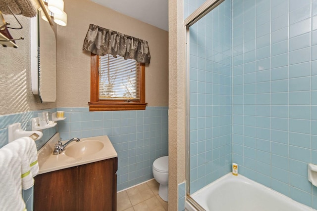 full bathroom featuring tile walls, tiled shower / bath combo, vanity, toilet, and tile patterned floors