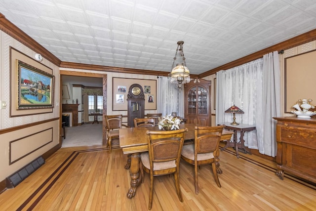 dining area with crown molding, a notable chandelier, and light hardwood / wood-style floors