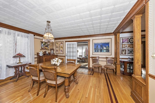 dining area with a notable chandelier, ornamental molding, and light hardwood / wood-style floors