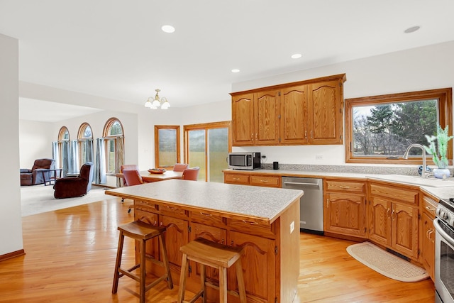 kitchen with sink, a breakfast bar area, a center island, appliances with stainless steel finishes, and light hardwood / wood-style floors