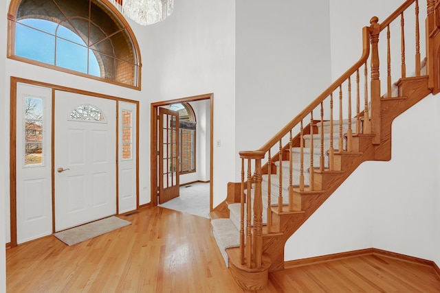 entrance foyer featuring a towering ceiling, wood-type flooring, and a chandelier