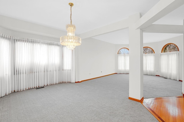 unfurnished room featuring light colored carpet, a chandelier, and a healthy amount of sunlight