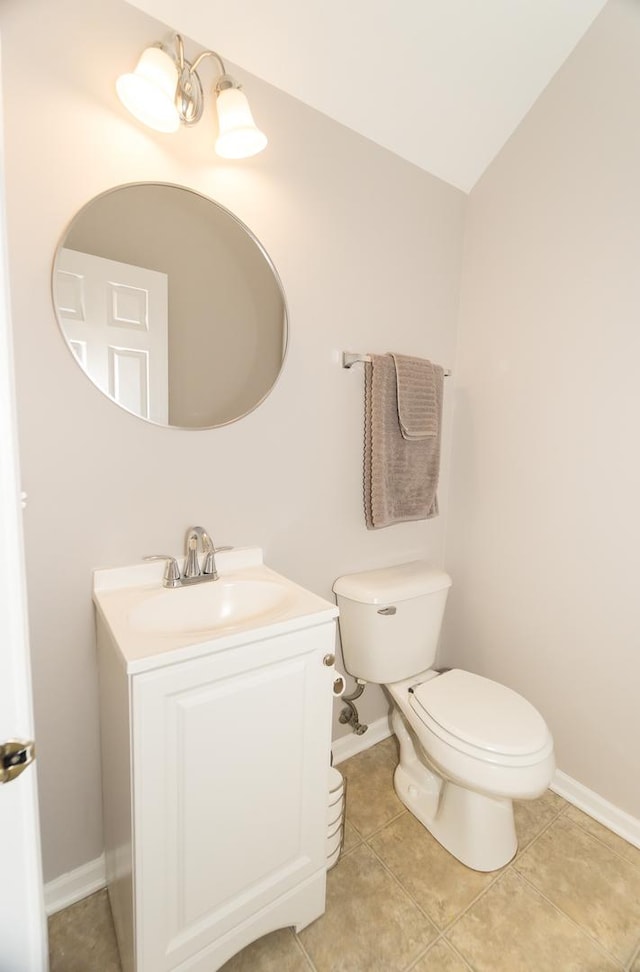 bathroom with tile patterned flooring, vanity, lofted ceiling, and toilet