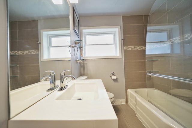 full bathroom featuring vanity, tiled shower / bath combo, and toilet