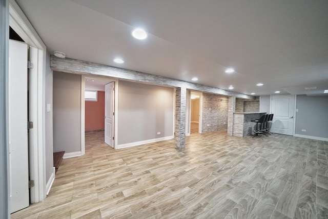 basement featuring light hardwood / wood-style floors and indoor bar