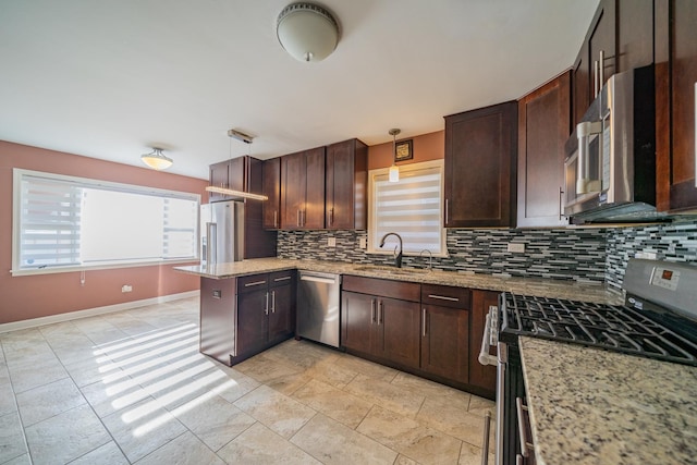 kitchen featuring sink, appliances with stainless steel finishes, backsplash, light stone countertops, and decorative light fixtures