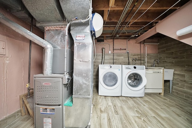 laundry area featuring independent washer and dryer, wood-type flooring, and heating unit