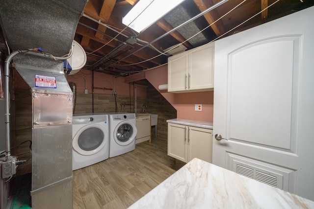 laundry room with cabinets, independent washer and dryer, and light wood-type flooring