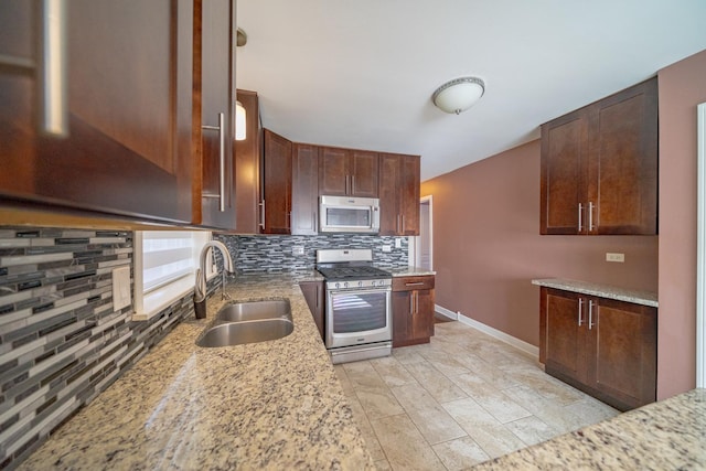 kitchen featuring stainless steel appliances, sink, light stone counters, and decorative backsplash