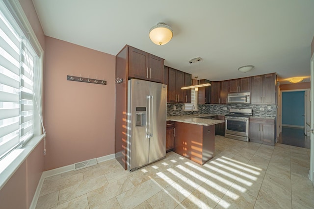 kitchen with sink, tasteful backsplash, decorative light fixtures, dark brown cabinets, and appliances with stainless steel finishes