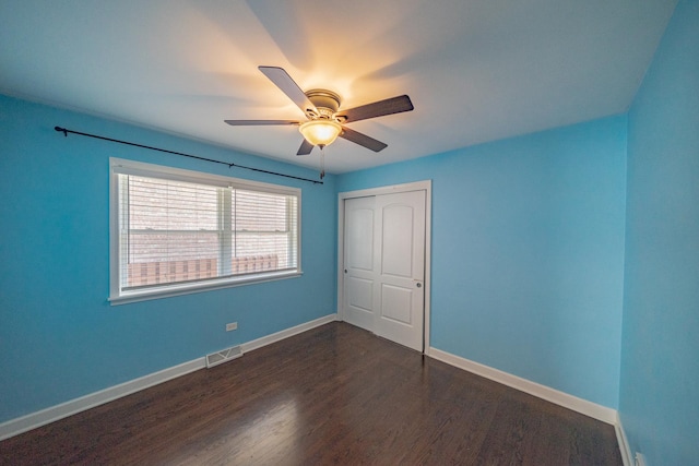 unfurnished bedroom with dark hardwood / wood-style flooring, a closet, and ceiling fan