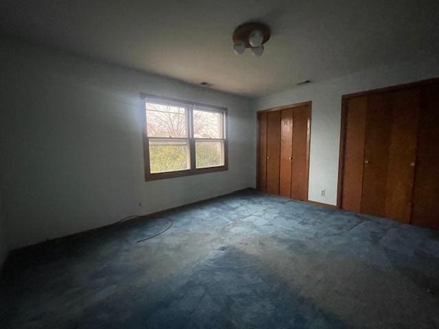 unfurnished bedroom featuring multiple closets and carpet floors