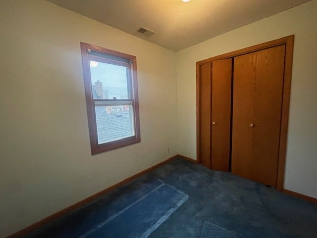 unfurnished bedroom with dark carpet and a closet