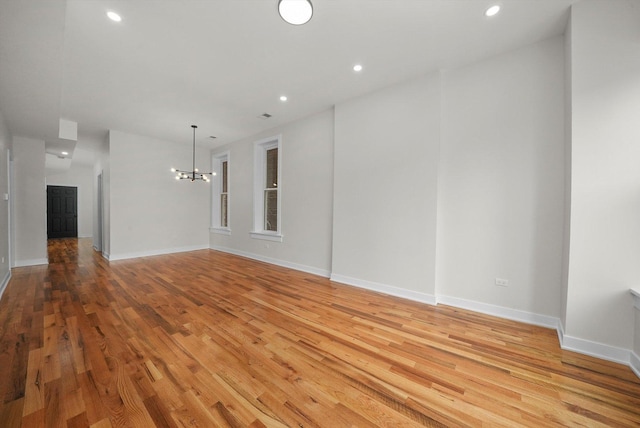 empty room featuring hardwood / wood-style flooring and a chandelier