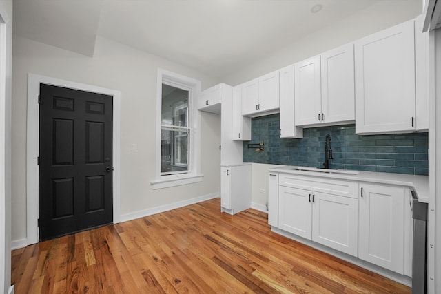 kitchen featuring white cabinetry, sink, light wood-type flooring, and backsplash