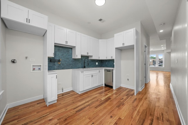 kitchen featuring sink, decorative backsplash, light hardwood / wood-style flooring, and white cabinets