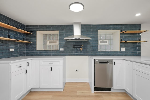 kitchen with dishwasher, white cabinets, decorative backsplash, wall chimney range hood, and light hardwood / wood-style flooring