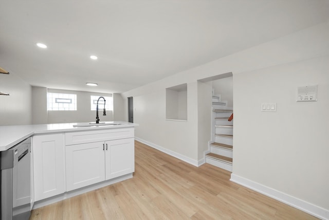 kitchen featuring dishwasher, sink, white cabinets, kitchen peninsula, and light hardwood / wood-style flooring