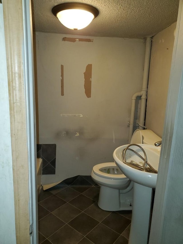 bathroom with tile patterned flooring, a textured ceiling, and toilet