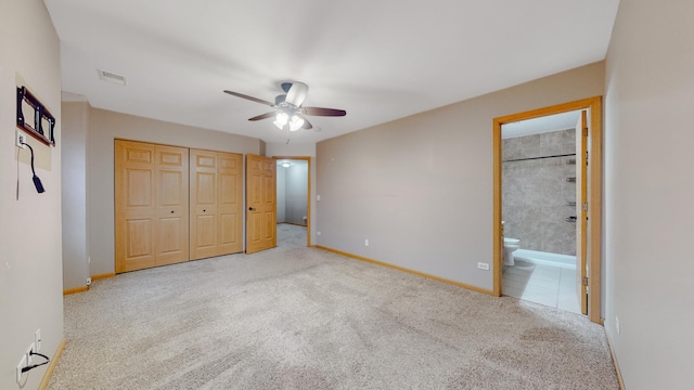 unfurnished bedroom featuring ceiling fan, light carpet, ensuite bath, and a closet