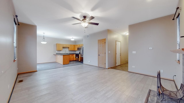 living room featuring ceiling fan, sink, and light wood-type flooring