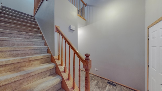 staircase featuring a high ceiling and hardwood / wood-style floors