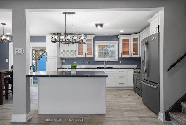 kitchen featuring sink, an inviting chandelier, pendant lighting, stainless steel appliances, and white cabinets