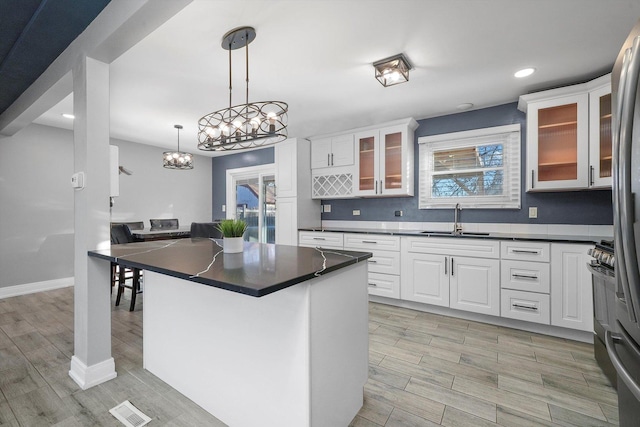 kitchen featuring sink, hanging light fixtures, a center island, stainless steel range oven, and white cabinets