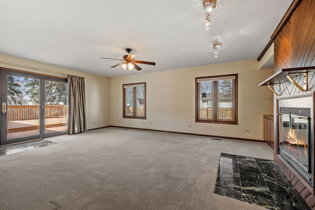 unfurnished living room with light carpet, a glass covered fireplace, ceiling fan, and baseboards