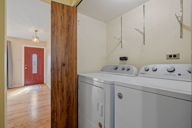 clothes washing area with light wood finished floors, laundry area, washing machine and dryer, and baseboards