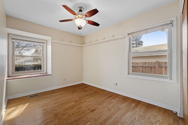 empty room featuring visible vents, a healthy amount of sunlight, and wood finished floors