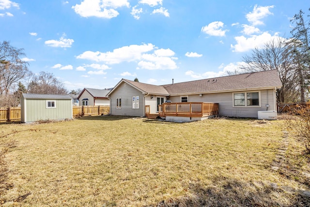 rear view of property featuring a deck, an outdoor structure, a fenced backyard, and a lawn