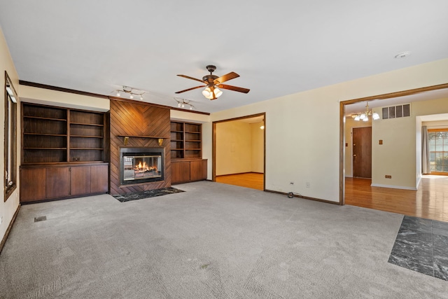 unfurnished living room with visible vents, light colored carpet, built in shelves, and a fireplace with flush hearth