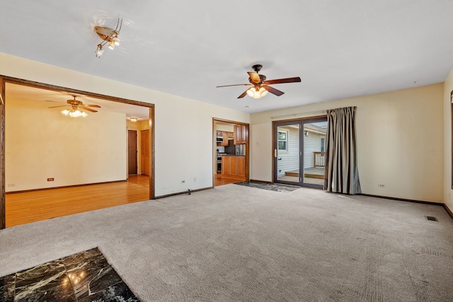 carpeted spare room featuring a ceiling fan, visible vents, and baseboards