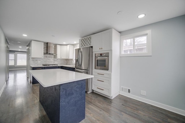 kitchen with stainless steel appliances, white cabinets, a kitchen island, dark hardwood / wood-style flooring, and wall chimney exhaust hood