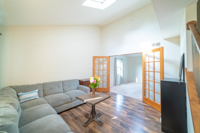 living room with dark hardwood / wood-style flooring, french doors, and vaulted ceiling with skylight