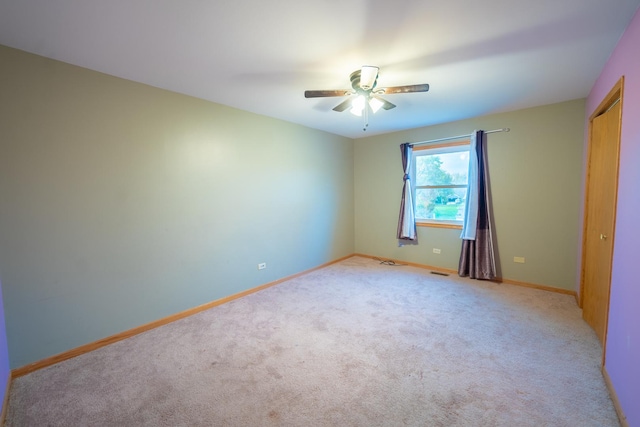 spare room with ceiling fan and light colored carpet